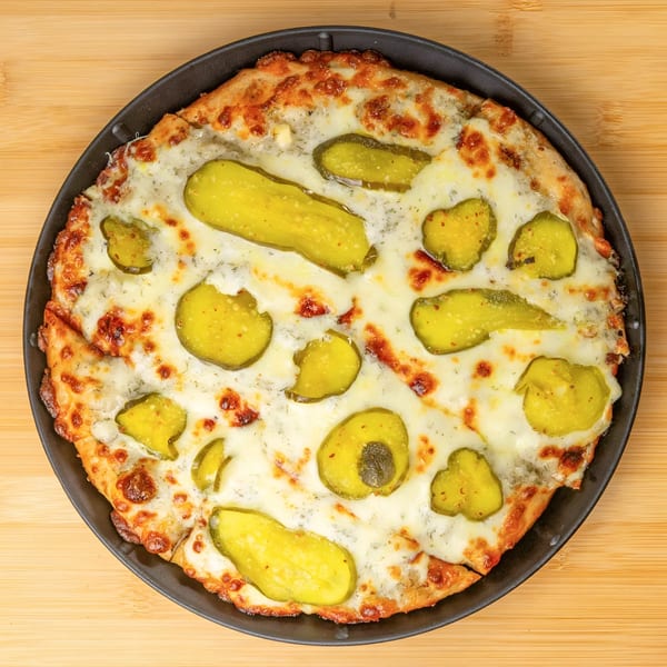 Overhead view of a pickle pizza from Cameo at the Fieldhouse, with melted cheese and dill.