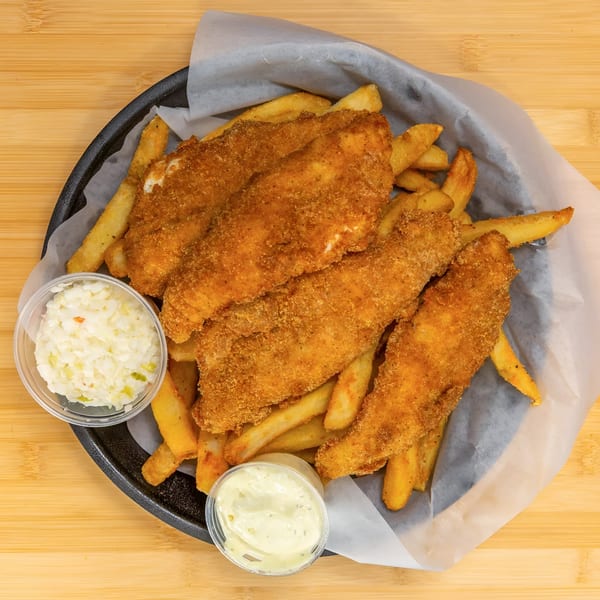 Crispy fried fish fillets and golden french fries in a basket with coleslaw and tartar sauce.