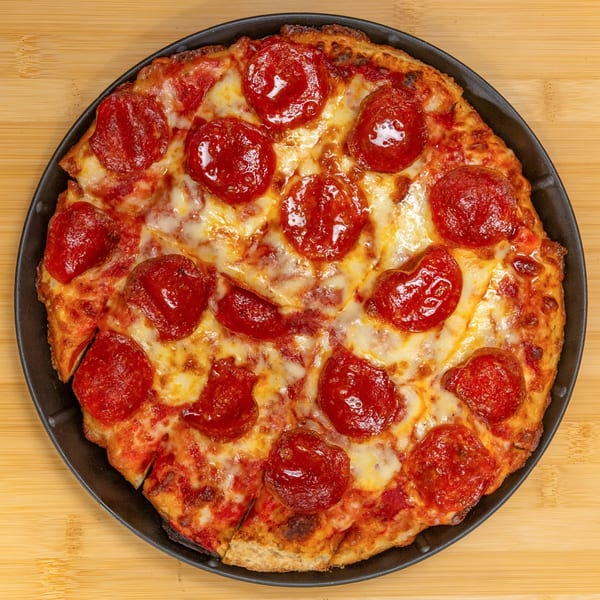 A freshly baked pepperoni pizza from Cameo at the Fieldhouse, sliced and served in a black pan.