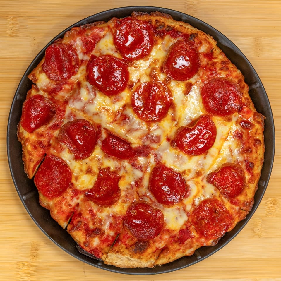 A freshly baked pepperoni pizza from Cameo at the Fieldhouse, sliced and served in a black pan.